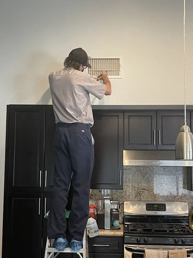 Technician inspecting an air vent during HVAC service in Milltown